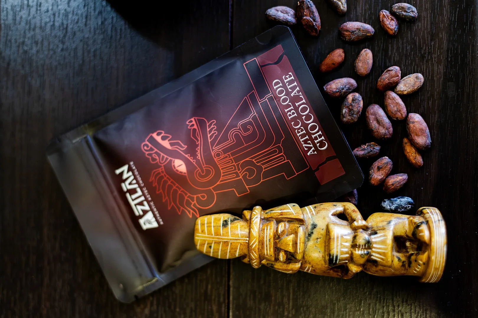 Top-down view of AztecBlood pouch, cacao beans, and Aztec idol